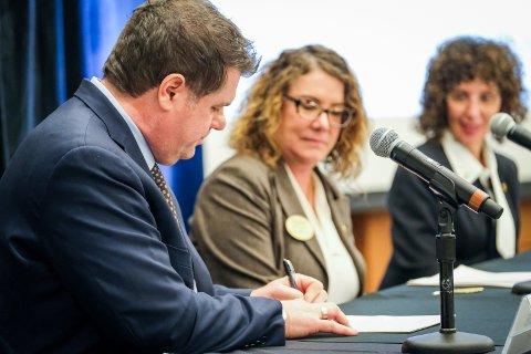 Easterseals MORC and OU representatives signing documents at a table with microphones